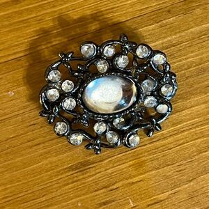 Crystal cat’s eye brooch surrounded by rhinestones, filigree on gun metal 1 1/2”